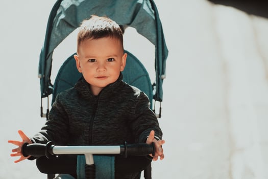 Sweet baby boy in a stroller bicycle outdoors. Little child in a pram. Infant kid in a pushchair. Spring walks with kids. photo