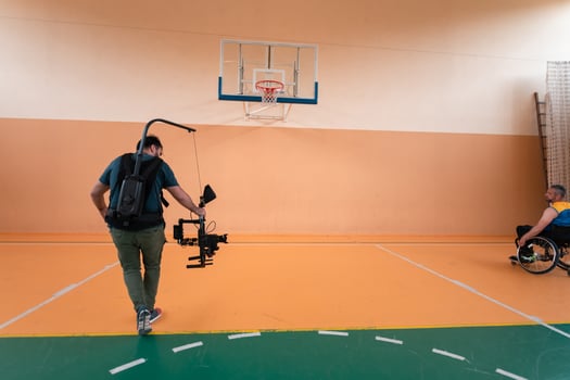a cameraman with professional equipment records a match of the national team in a wheelchair playing a match in the arena photo
