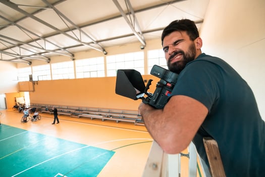 a cameraman with professional equipment records a match of the national team in a wheelchair playing a match in the arena photo