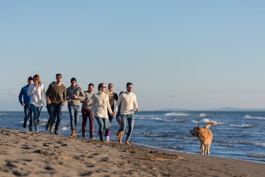 Group of friends running on beach during autumn day photo