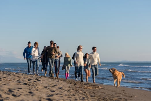 Group of friends running on beach during autumn day photo