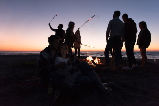 Couple enjoying bonfire with friends on beach photo