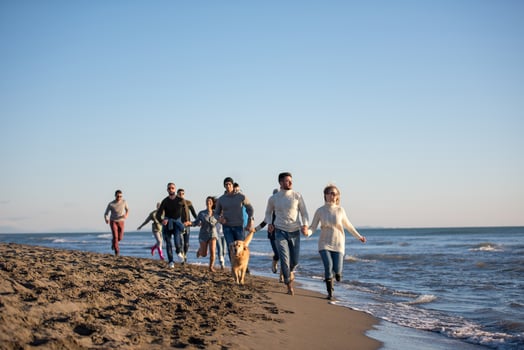Group of friends running on beach during autumn day photo