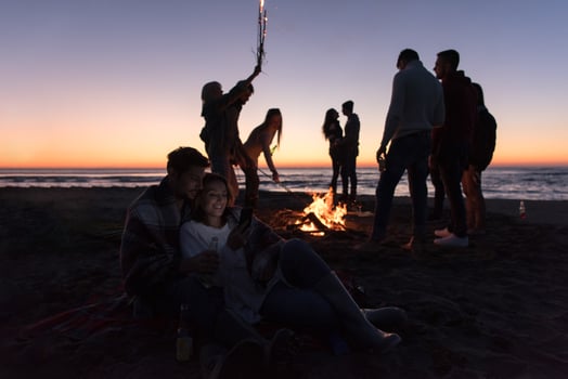 Couple enjoying bonfire with friends on beach photo