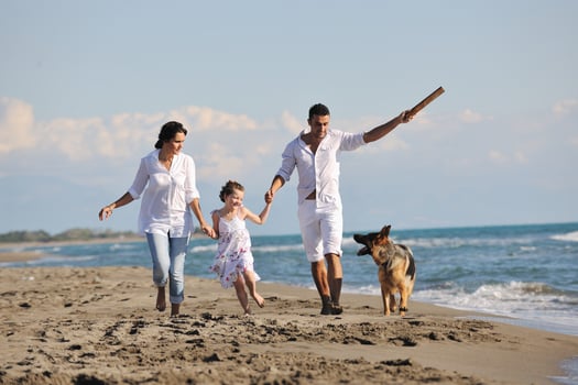 happy family playing with dog on beach photo