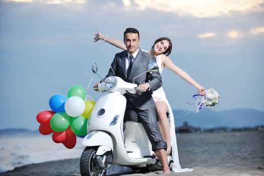 just married couple on the beach ride white scooter photo