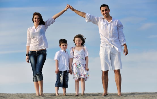 family on beach showing home sign photo
