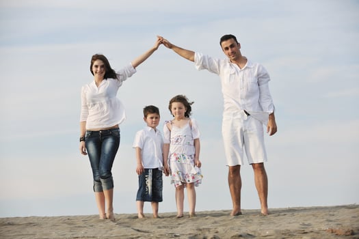 family on beach showing home sign photo