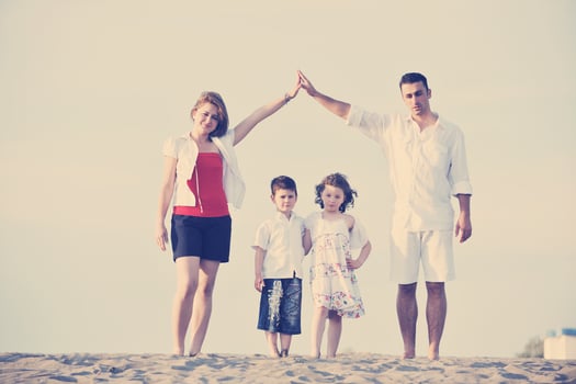 family on beach showing home sign photo