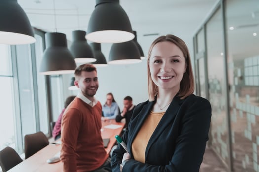Portrait of happy businesswoman and businessman in modern office. Businessman and businesswoman smiling and looking at camera. Busy diverse team working in background. Leadership concept. Head shot. photo