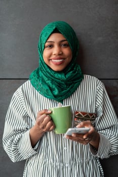 African Muslim businesswoman with green hijab using mobile phone during coffee break from work outside photo