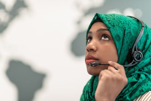 Afro Muslim female with green hijab scarf customer representative business woman with phone headset helping and supporting online with customer in modern call centre photo