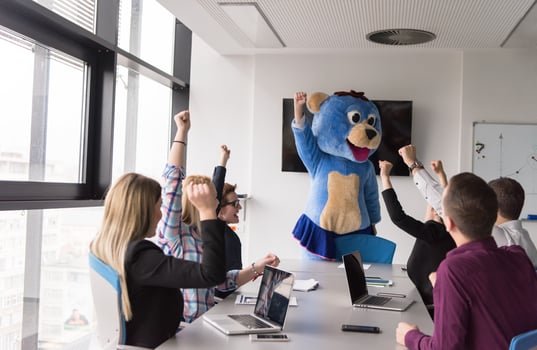 boss dresed as bear having fun with business people in trendy office photo