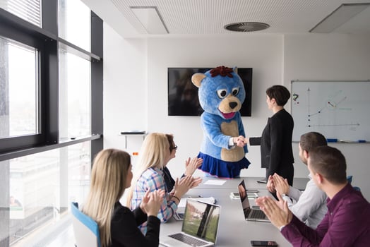 boss dresed as bear having fun with business people in trendy office photo
