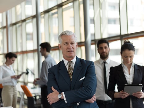 portrait of senior businessman as leader  with staff in background photo