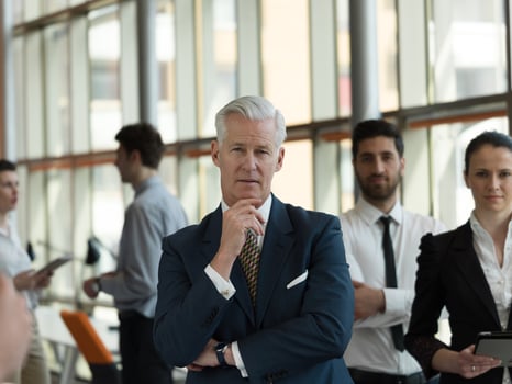 portrait of senior businessman as leader  with staff in background photo