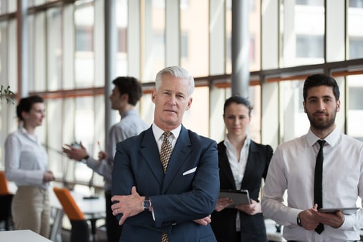 portrait of senior businessman as leader  with group of people in background as team photo