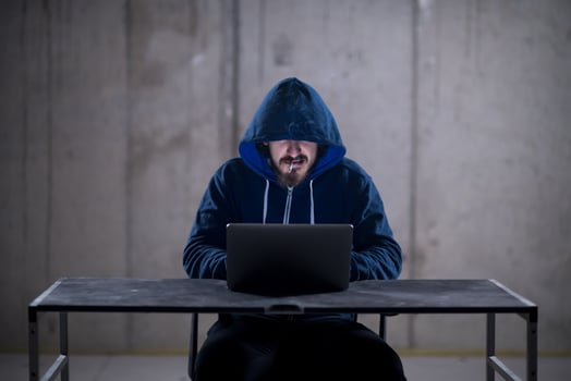 young hacker using laptop computer while working in dark office photo