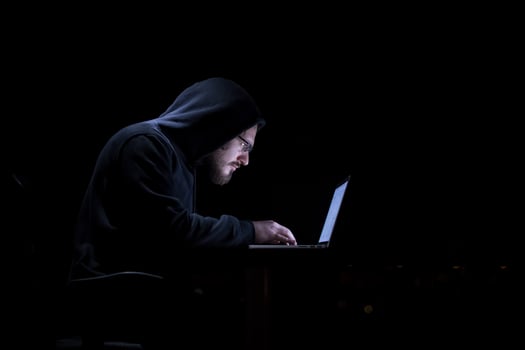 hacker using laptop computer while working in dark office photo