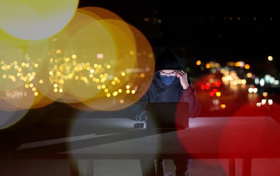 hacker using laptop computer while working in dark office photo