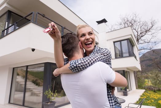 couple hugging in front of  new luxury home photo