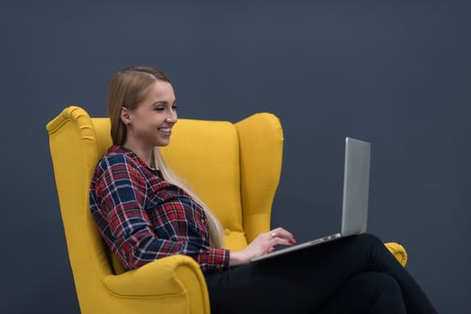 startup business, woman  working on laptop and sitting on yellow armchair photo