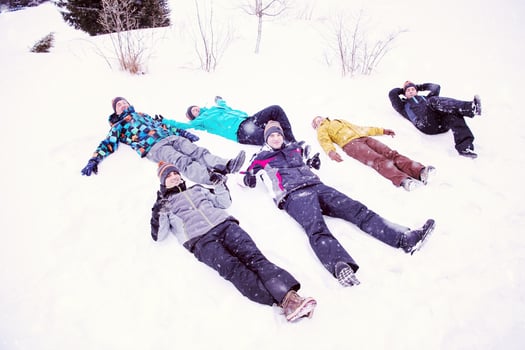 group of young people laying on snow and making snow angel photo