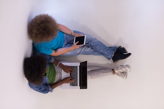 multiethnic couple sitting on the floor with a laptop and tablet top view photo