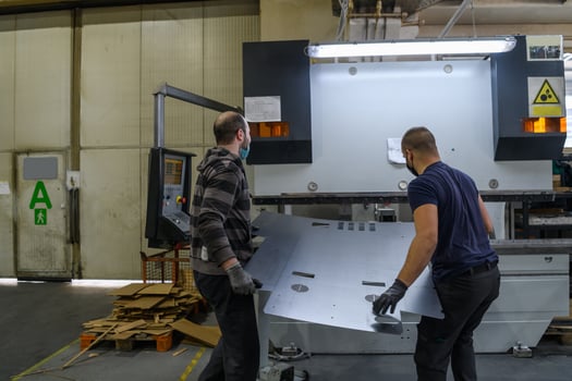 two workers wearing a protective mask due to a coronavirus pandemic, working in a modern factory and preparing a program and materials for a cnc machine photo