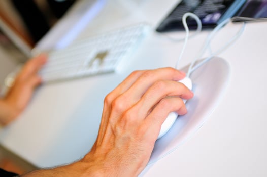 lose-up of male hand on mouse while working on laptop photo