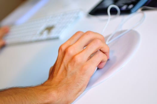lose-up of male hand on mouse while working on laptop photo