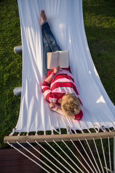 woman reading a book while relaxing on hammock photo