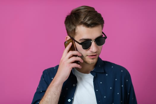 a young man wearing a blue shirt and sunglasses using a smartphone photo