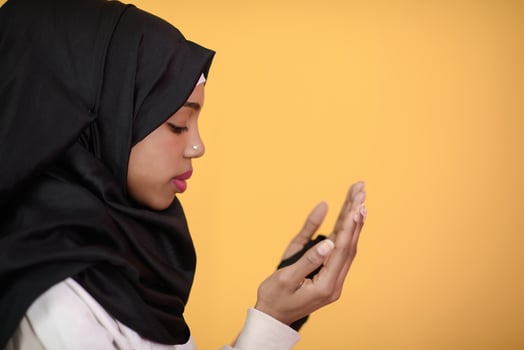 African Muslim woman makes traditional prayer to God, keeps hands in praying gesture, wears traditional white clothes photo