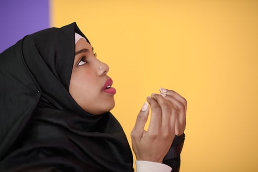 African Muslim woman makes traditional prayer to God, keeps hands in praying gesture, wears traditional white clothes photo