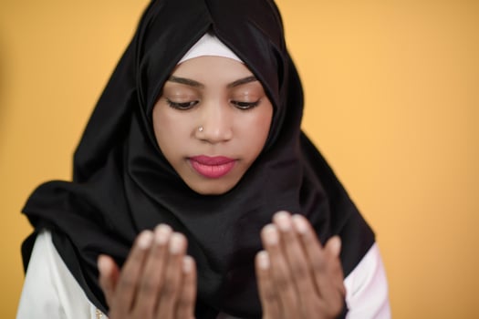 African Muslim woman makes traditional prayer to God, keeps hands in praying gesture, wears traditional white clothes photo