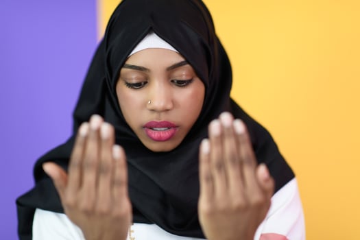African Muslim woman makes traditional prayer to God, keeps hands in praying gesture, wears traditional white clothes photo