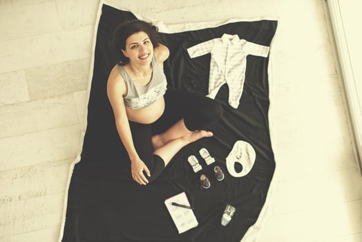 top view of pregnant woman checking list of baby clothes photo