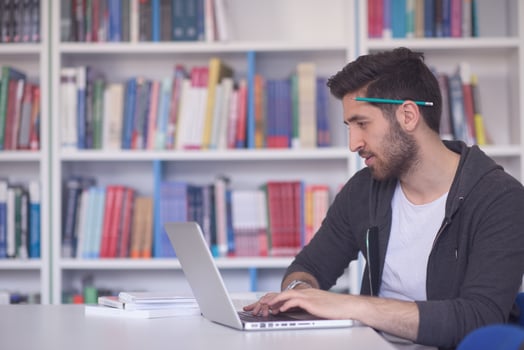 student in school library using laptop for research photo