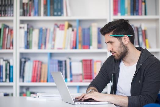 student in school library using laptop for research photo
