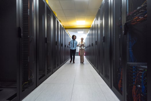 engineer showing working data center server room to female chief photo