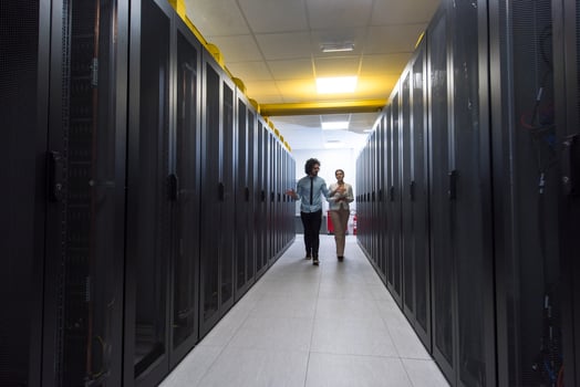 engineer showing working data center server room to female chief photo