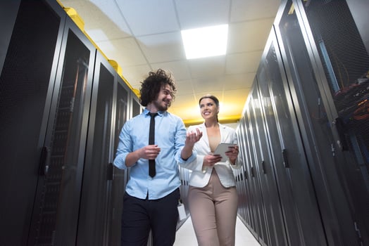 engineer showing working data center server room to female chief photo