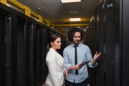 engineer showing working data center server room to female chief photo