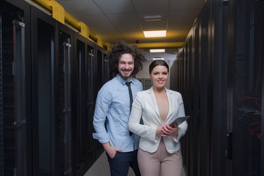 engineer showing working data center server room to female chief photo