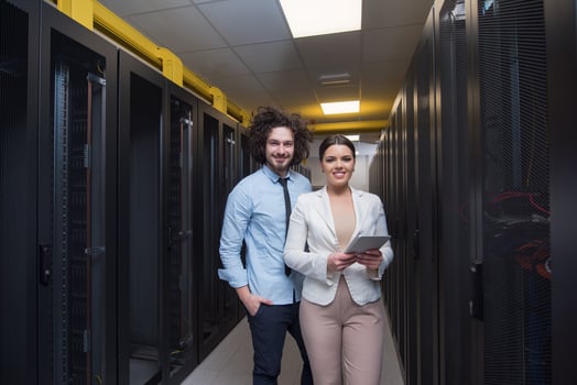 engineer showing working data center server room to female chief photo