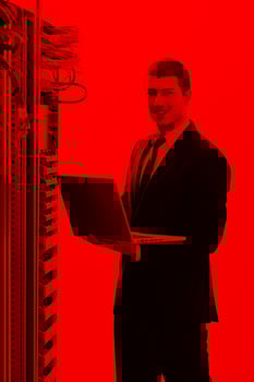 businessman with laptop in network server room photo