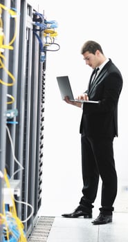 businessman with laptop in network server room photo