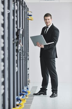 businessman with laptop in network server room photo