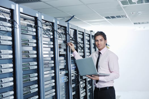 businessman with laptop in network server room photo